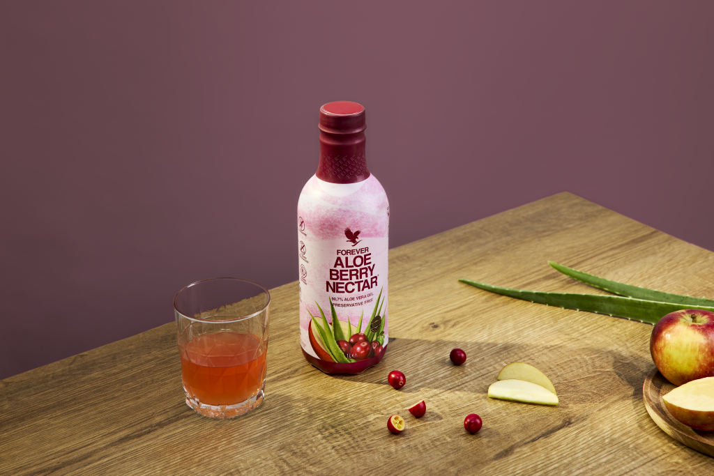 Aloe Berry Nectar en bouteille avec verre de boisson à l’aloe vera et fruits rouges sur table en bois